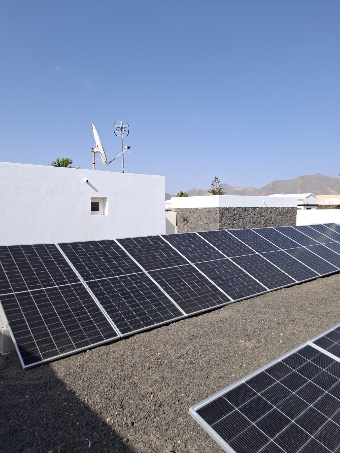 Solar panels beside a white villa wall