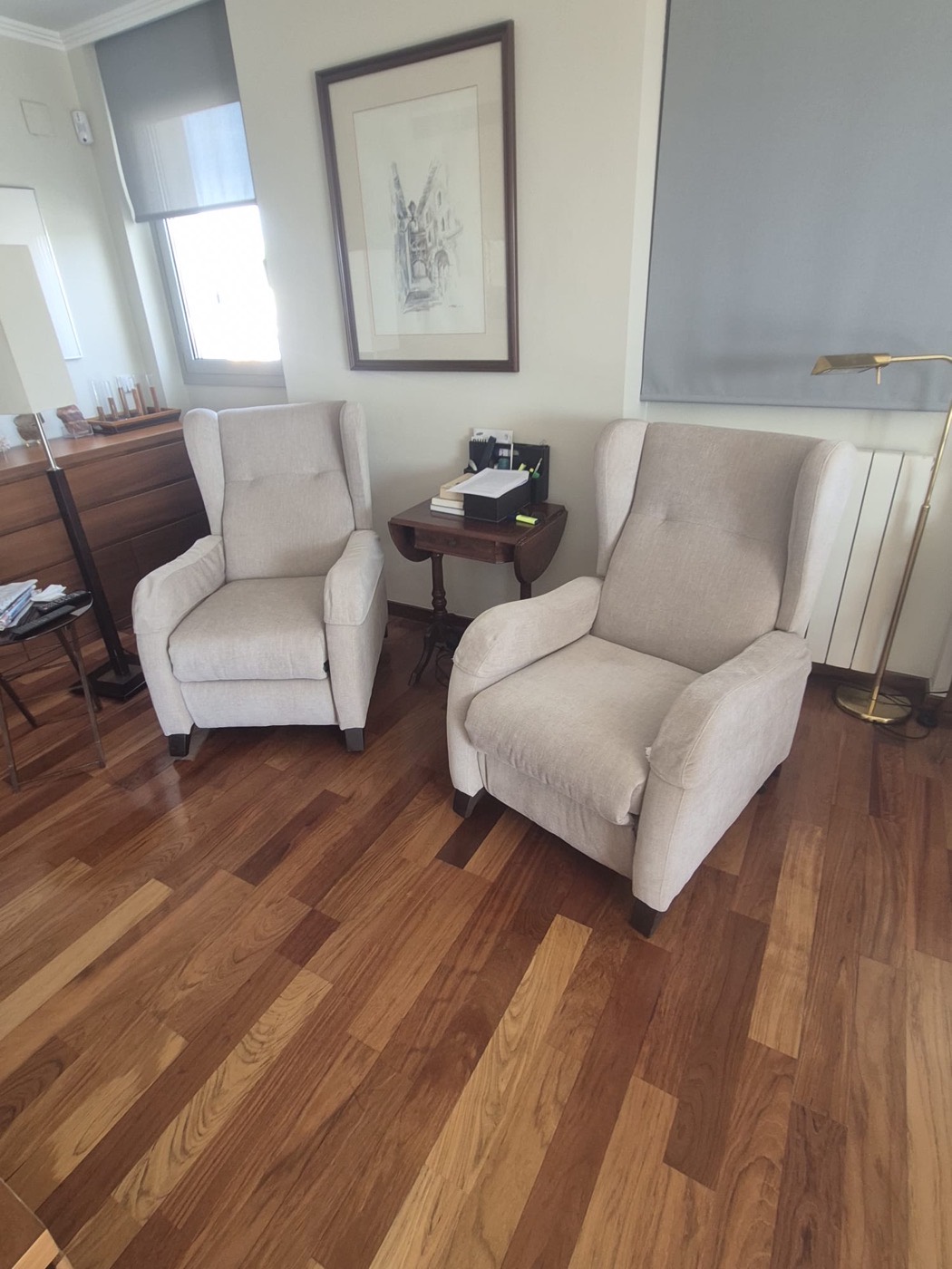 Pareja de butacas orejeras tapizadas en beige en un salón de Girona