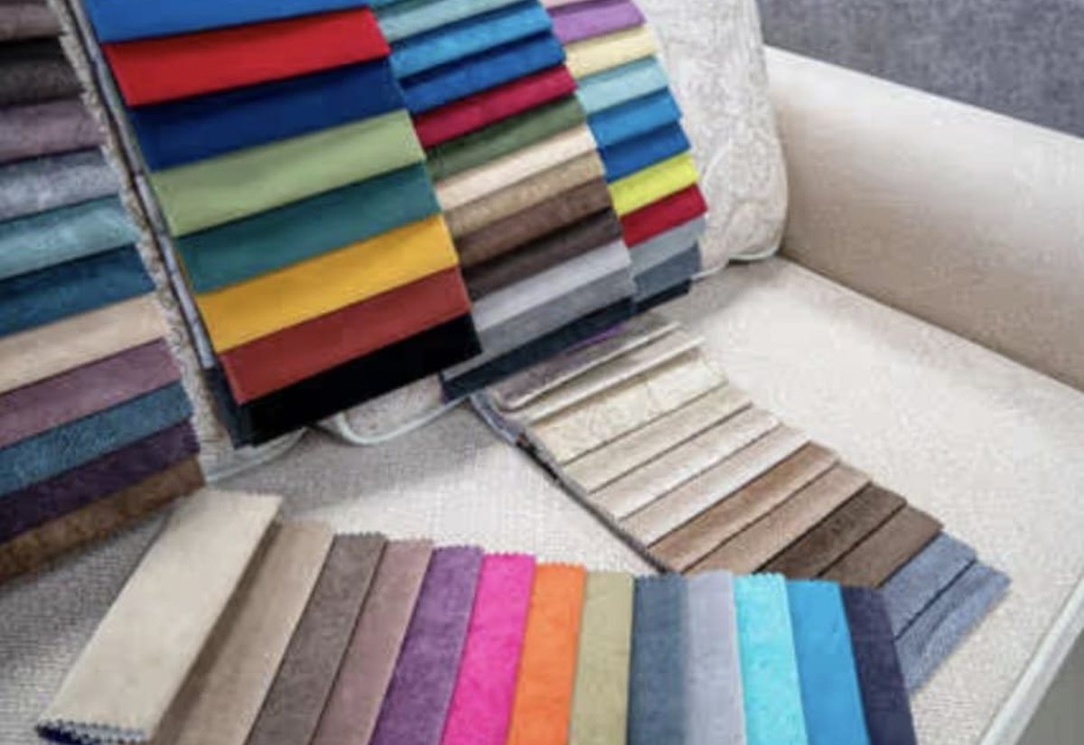 Muestrario de telas de tapicería en decenas de colores sobre un sofá del taller